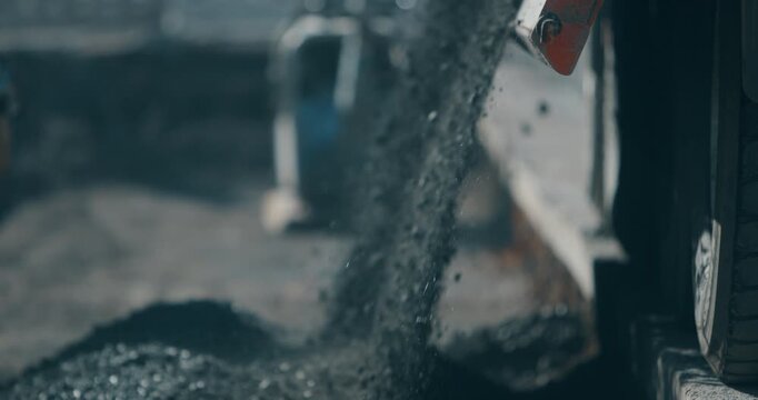 Asphalt dumping from truck bed at road construction site