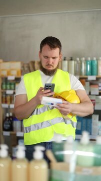  Young man builder in uniform scanning qr code for box of ointment in pharmacy 