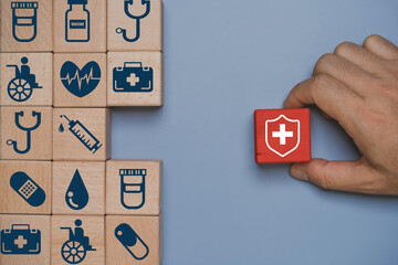 Healthcare insurance protection concept with medical icons on wooden blocks and red shield symbol. Health safety coverage, risk management and medical support strategy theme with copy space.