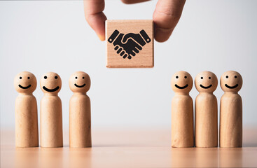 Business partnership and customer relationship concept with wooden figures and handshake icon. Trust building, teamwork collaboration and agreement strategy theme symbolizing cooperation and loyalty.