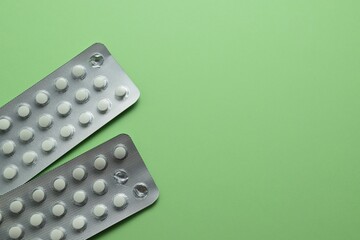 Two blister packs of tablets on a green background