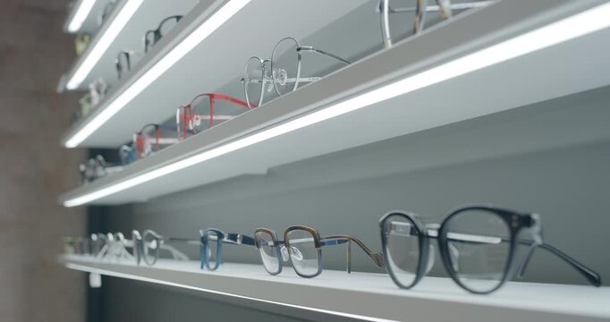 Row of eyeglasses on illuminated shelves in optical store