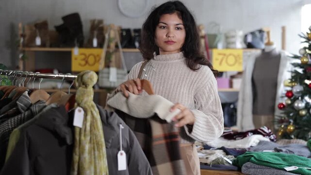 Woman chooses coat or jacket for the winter period in a fashionable clothing store. High quality 4k footage