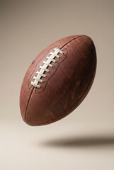 Naklejka premium A classic brown leather football with white laces floats against a neutral background with a subtle shadow.