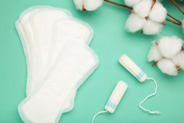 Sanitary pad and cotton flower on mint background. Daily feminine hygiene product. Menstruation and womens health concept. Copy space. © Mouse family