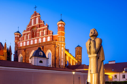 A Statue of the Polish Poet Adam Mickiewicz in front of St. Anne's Church and the Church of St. Francis and St. Bernard at Dusk, Vilnius, Lithuania
