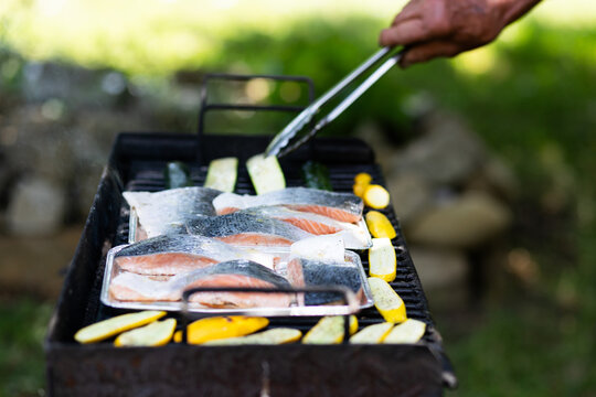 Grilling salmon fillets on a barbecue with vegetables on a sunny day in Romania