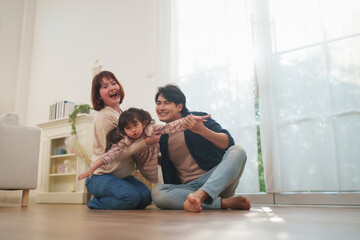 Happy Asian family playing together on floor at home