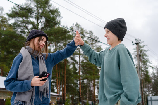 teenage girl and boy slap hands in a high five. Focus is on hands and faces from below, symbolizing triumph, mutual support, and culmination of shared running workout for fitness and health.