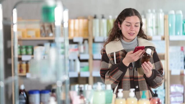 Girl in winter clothes scans code on cough syrup to check the expiration date. High quality 4k footage