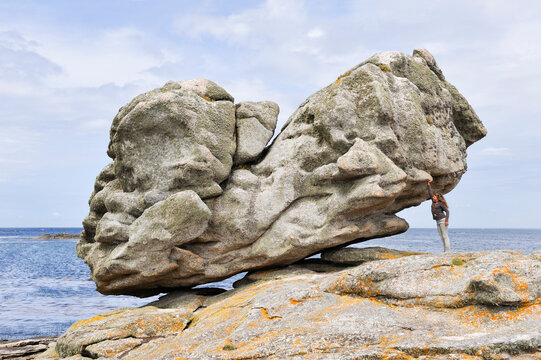 Young girl simulating holding one of the remarkable rocks on Ile de Sein, off the coast of Pointe du Raz, Finistere department, Brittany region, France