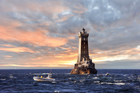Sea bass fishing boat beside the lighthouse of La Vieille, Pointe du Raz, Cap Sizun, Finistere department, Brittany region, France
