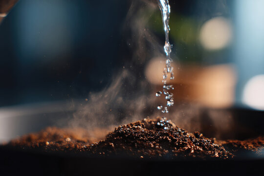 A close-up capture of water droplets falling onto coffee grounds, creating a visually engaging moment filled with rich textures and the promise of a fresh brew coming alive.