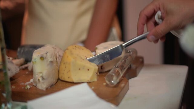 Close up of hand slicing artisanal gourmet cheese on wooden board at luxury catering event