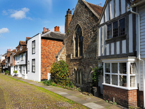 Historic architecture along a cobblestone street lined with homes in Rye East Sussex under clear blue skies