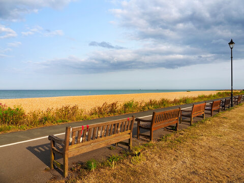 Benches line the path along the beach at Deal in Kent with a view of the sea and sky