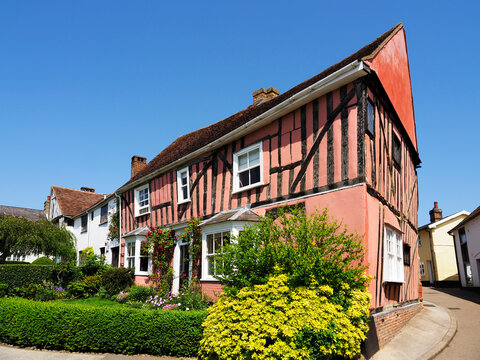 Timber framed house with a pink exterior and garden in Lavenham, Suffolk on a clear day