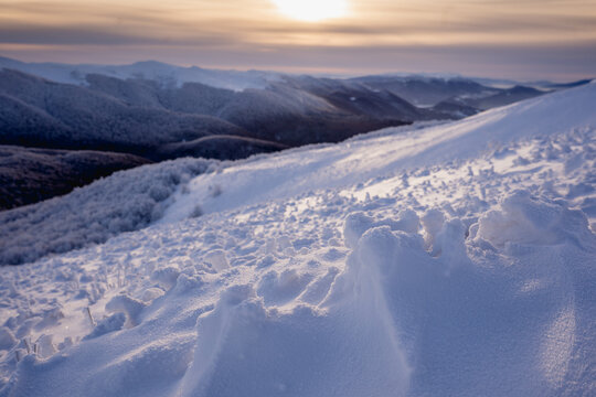 Snow covered ridge trail in the Bieszczady during a cold winter morning with blue sky, golden hour light and panoramic mountain views.
