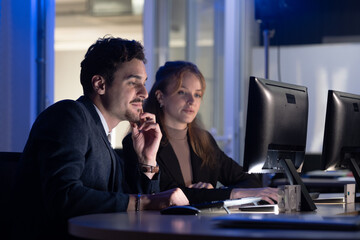 Fototapeta premium Colleagues work together at computers in a modern office setting during evening hours