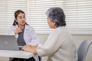 Obraz premium Elderly patient consulting female doctor in clinic, symptom talk and diagnosis with laptop technology, digital health records, advice communication, trust, aging care appointment, wellness health