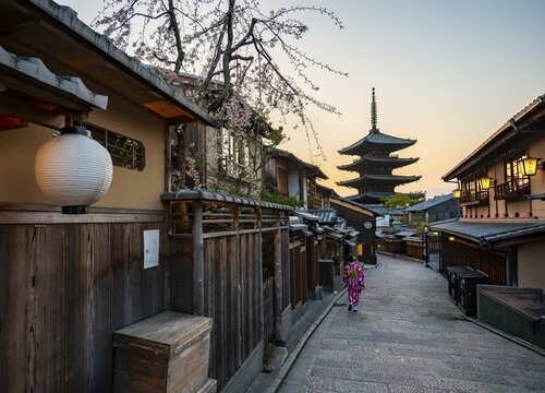 Japanese woman in kimono in an alley, Yasaka dori historic alleyway in the old town with traditional Japanese houses, five-story Yasaka Pagoda of the Buddhist Hōkanji Temple in the back, evening mood, sunset, Higashiyama, Kyoto, Japan
