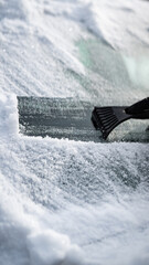 Scraping ice and snow from car windshield with plastic scraper on a cold winter day © BMH-Production