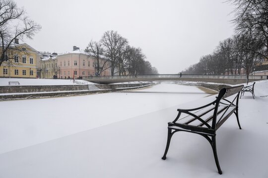 Bench, historic buildings on the frozen Aurajoki River, wintery Turku or Swedish &Aring;bo, Varsinais-Suomi, Finland
