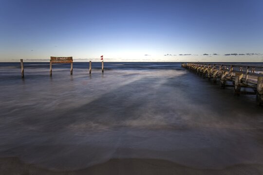 Wooden sign in the sea with inscription Zingst and wooden walkway, long exposure, evening light, Zingst, Fischland-Dar&szlig;-Zingst, Western Pomerania National Park, Mecklenburg-Western Pomerania, Germany