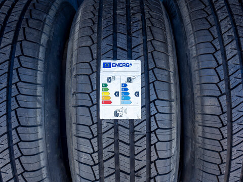 Close-up of new car tires with EU energy efficiency label attached. Detailed tread pattern texture visible on multiple stacked tires