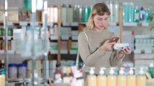Young woman buyer scanning qr code for box of ointment in pharmacy