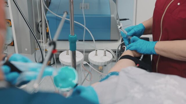 Surgeons performing a medical procedure in a hospital operating room while the patient lies on an operating table. Medical team in sterile uniforms working with surgical equipment in a controlled