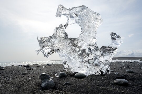 Ice, piece of ice with holes on the black sand beach, on the black lava beach Diamond Beach, southeast Iceland, Iceland