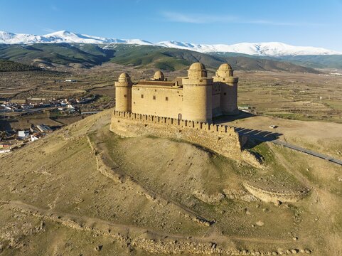 The Renaissance castle of La Calahorra against the snow-capped Sierra Nevada mountain range, aerial view, drone shot, Granada province, Andalusia, Spain