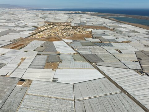 The town of San Agustin amidst masses of shimmering plastic greenhouses, on the right the shallow lagoon Salinas de Cerrillos, aerial view, drone shot, Almer&iacute;a province, Andalusia, Spain
