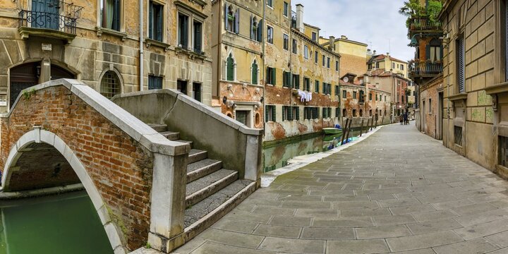 Arched bridge over the old town canal, alley with old couple, Venice, Veneto, Italy