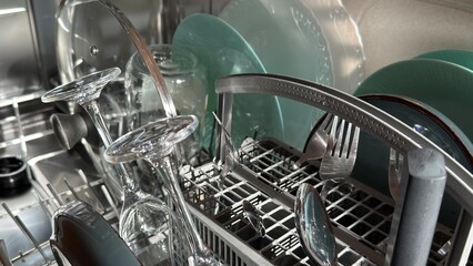 Obraz premium Dishwasher finished cycle, clean sparkling plates, glasses, cutlery, close-up, real home shoot.