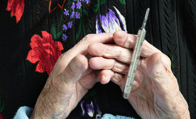 Elderly 90-year-old woman holding a mercury thermometer.