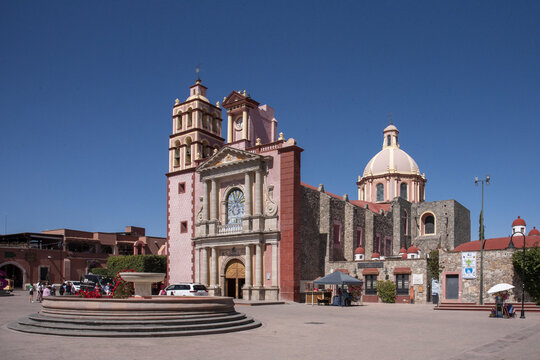Tequisquiapan, Mexico - 09 February 2025: View of the Parroquia de Santa Maria de la Asuncion bathed in warm sunlight, its pink hues contrasting with the clear blue sky above.