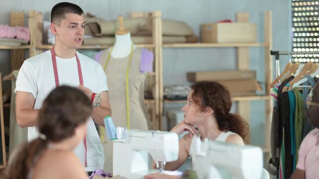 Experienced black sewing teacher guiding adult beginners in practical workshop