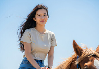 澄み渡る青空の下で馬に乗りカメラ目線で微笑む女性