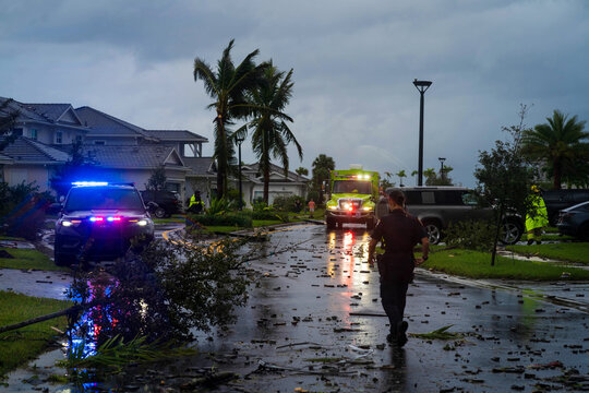 Palm Beach Gardens, United States - 09 October 2024: View of emergency vehicles amidst debris-strewn streets under a somber sky, highlighting the aftermath of a storm.