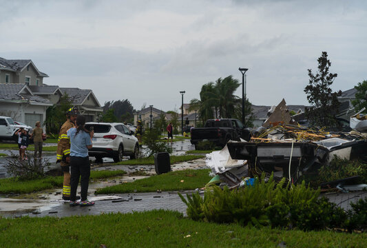 Palm Beach Gardens, United States - 09 October 2024: View of debris scattered across a residential street after a storm, with emergency personnel assessing the damage near Avenir Drive.