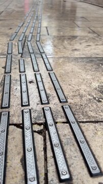 Closeup of tactile paving on weathered stone surface for visually impaired mobility background