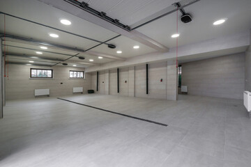 A large indoor area shows gray walls and tiled floor. It includes overhead lights and a few...