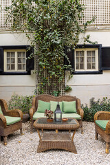 Cozy outdoor patio seating with wicker sofa and green cushions under climbing vines