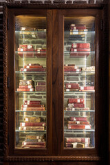 Antique red-bound books displayed in a wooden glass cabinet in Cairo library setting