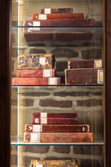 Antique red-bound books displayed in a wooden glass cabinet in Cairo library setting