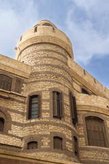 Historic stone tower architecture in Cairo with textured masonry and wooden shutters against blue sky