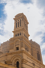 Historic stone church bell tower and Romanesque architecture in Cairo against cloudy blue sky