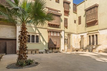 Sunny courtyard with palm tree and carved wooden balconies at the Coptic Museum in Cairo
